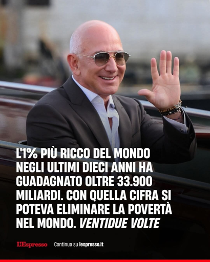 L'immagine mostra uJeff Bezos indossando occhiali da sole e un abito scuro con camicia bianca. Sta sorridendo e alza la mano destra in un gesto di saluto. Sullo sfondo, si intravede un'ambiente esterno, probabilmente un'area urbana. In basso, c'è un testo in italiano che recita: "L'1% più ricco del mondo negli ultimi dieci anni ha guadagnato oltre 33.900 miliardi. Con quella cifra si poteva eliminare la povertà nel mondo. Ventidue volte." In basso a sinistra, c'è il logo di "L'Espresso" e il testo "Continua su lespresso.it".


