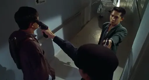 Three men standing in a corridor. Man on right in green jacket is pointing a pistol at the head of man at bottom right in peaked cap, who in turn is pointing a pistol at the head of man on left in brown jacket