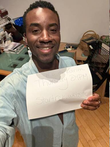 Karim Diané holding a piece of paper that says "startrek.website" thursday @ 4pm"